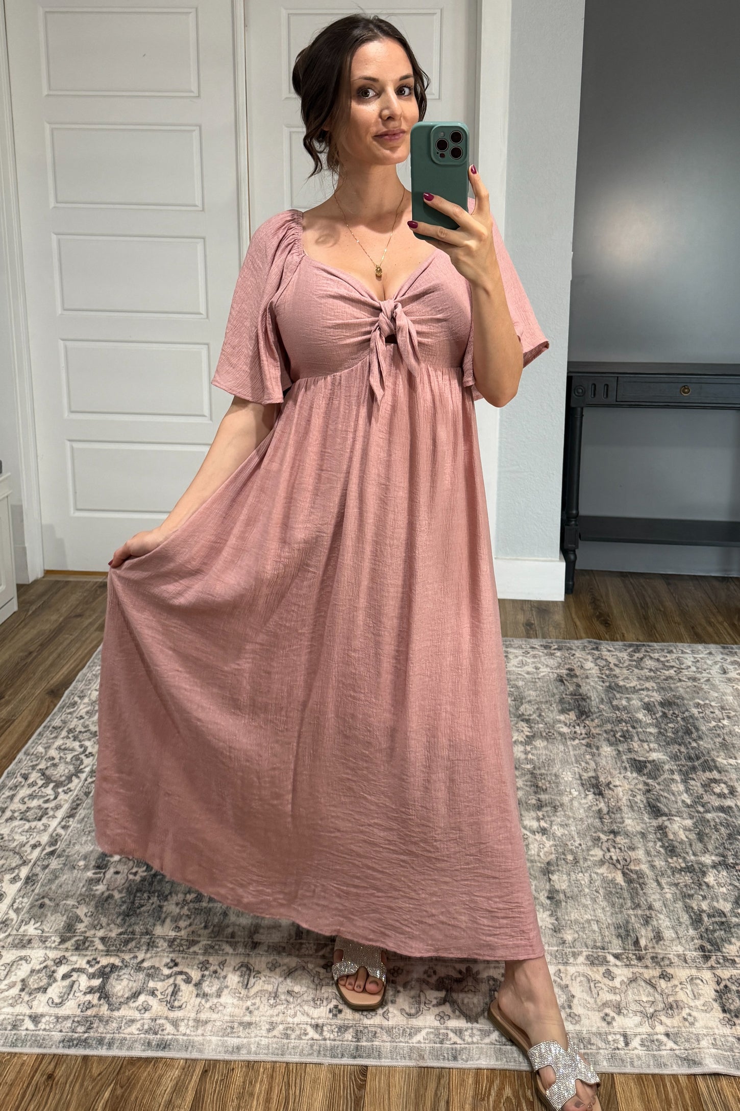 woman wearing a dusty rose maternity maxi dress with a knotted front and short flutter sleeves, showcasing her baby bump