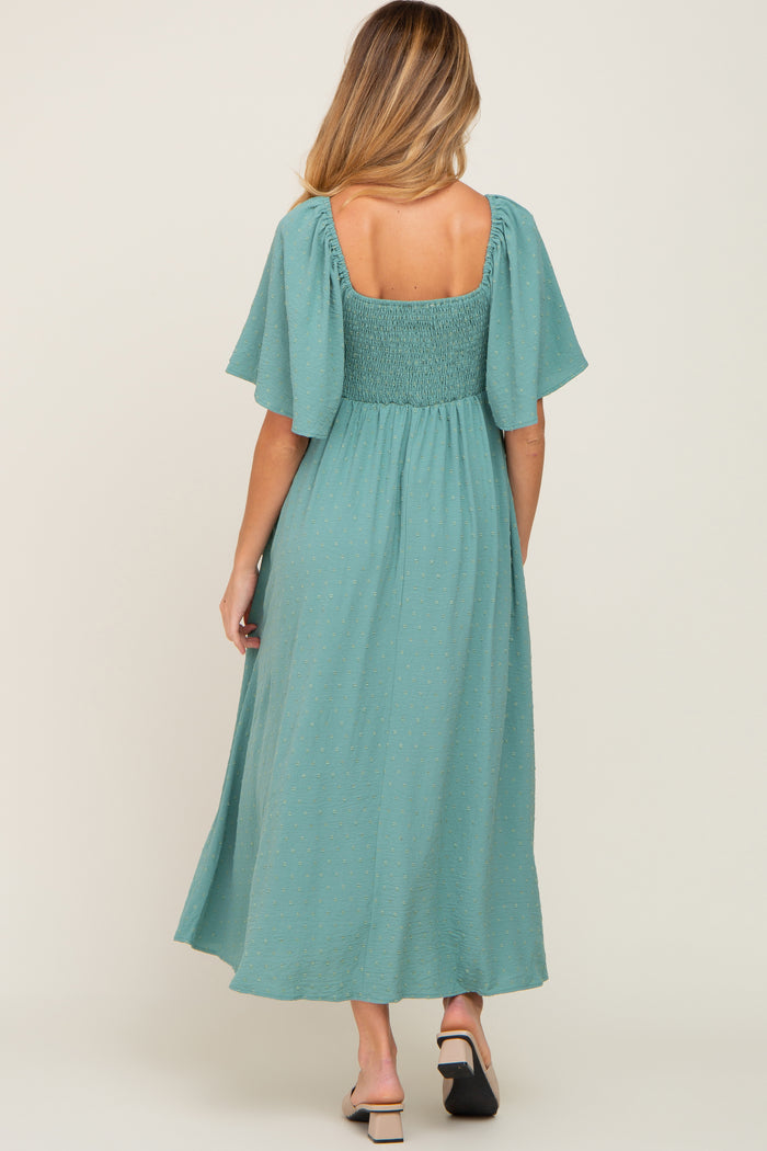 woman wearing a teal maternity dress with flutter sleeves and smocked bodice, showing a baby bump from the back