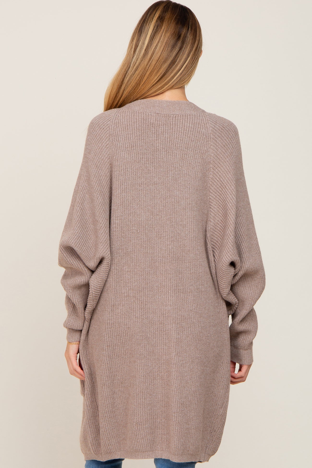 woman wearing a long, taupe maternity cardigan with balloon sleeves, shown from the back
