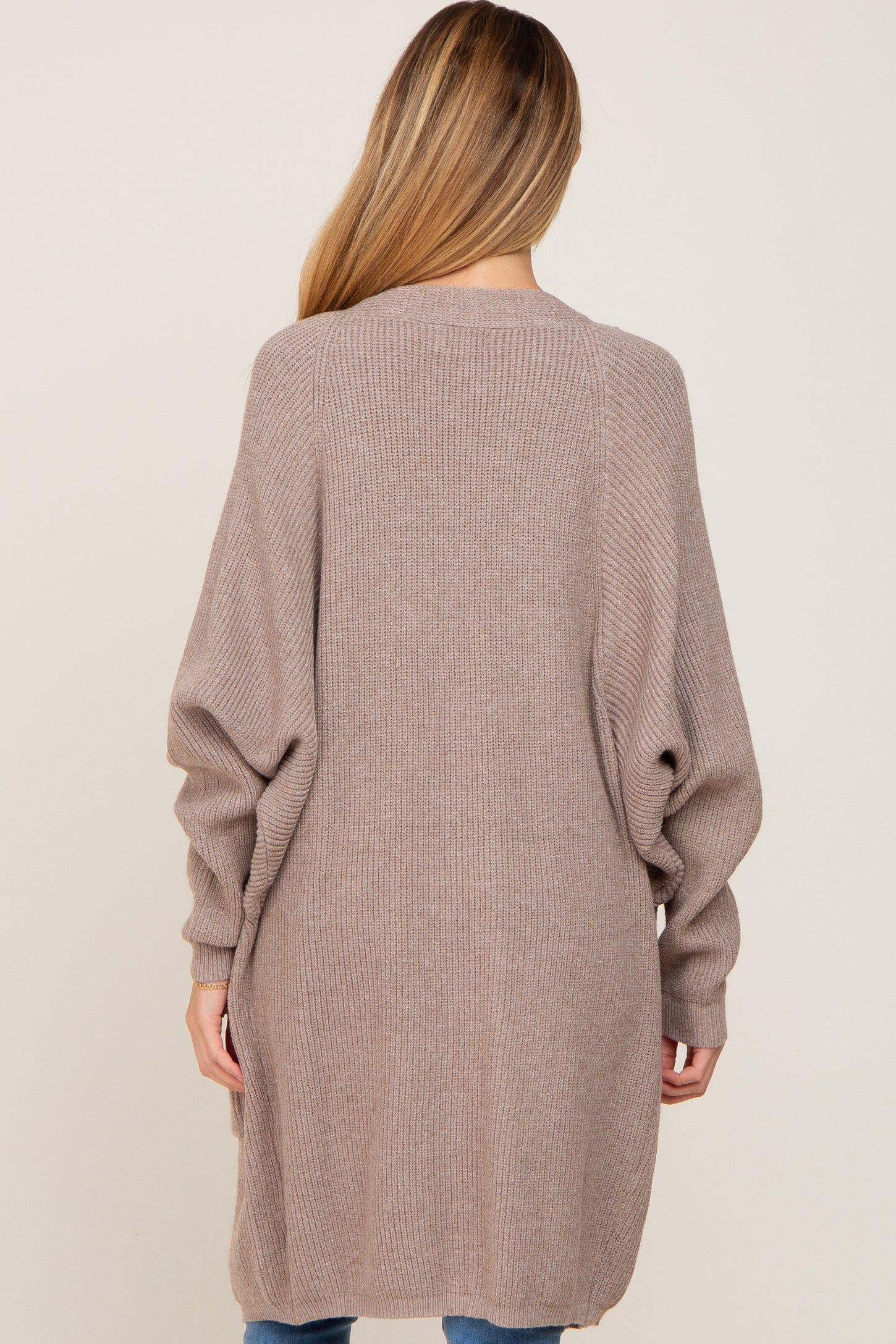 woman wearing a long, taupe maternity cardigan with balloon sleeves, shown from the back