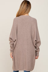 woman wearing a long, taupe maternity cardigan with balloon sleeves, shown from the back