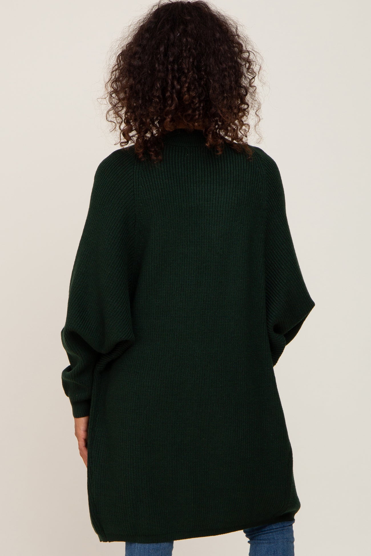 woman wearing a dark green oversized knit sweater with a relaxed fit and batwing sleeves