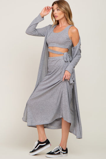 woman wearing a grey three-piece lounge set with a crop top, wrap skirt, and long cardigan