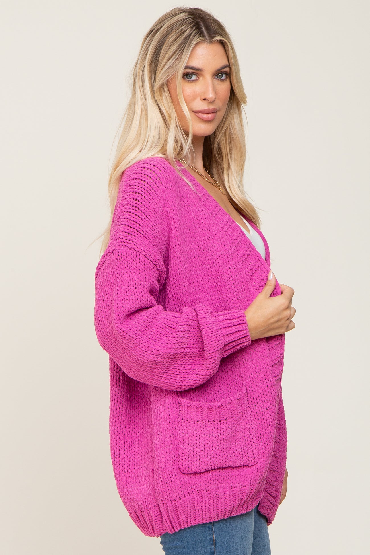 woman wearing a bright pink oversized knitted cardigan with pockets and a relaxed fit