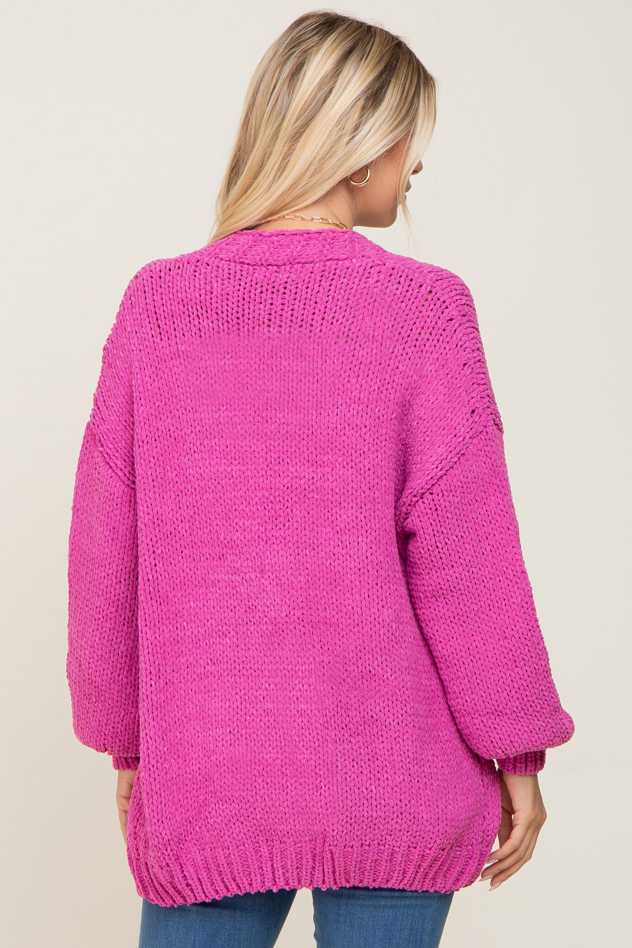 woman wearing a hot pink oversized knit sweater with balloon sleeves and a relaxed fit