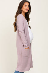 woman wearing a light pink maternity cardigan with pockets and a visible baby bump