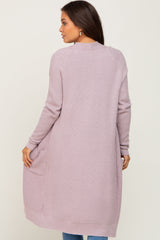 woman wearing a lilac long knit maternity cardigan with pockets, styled casually from the back