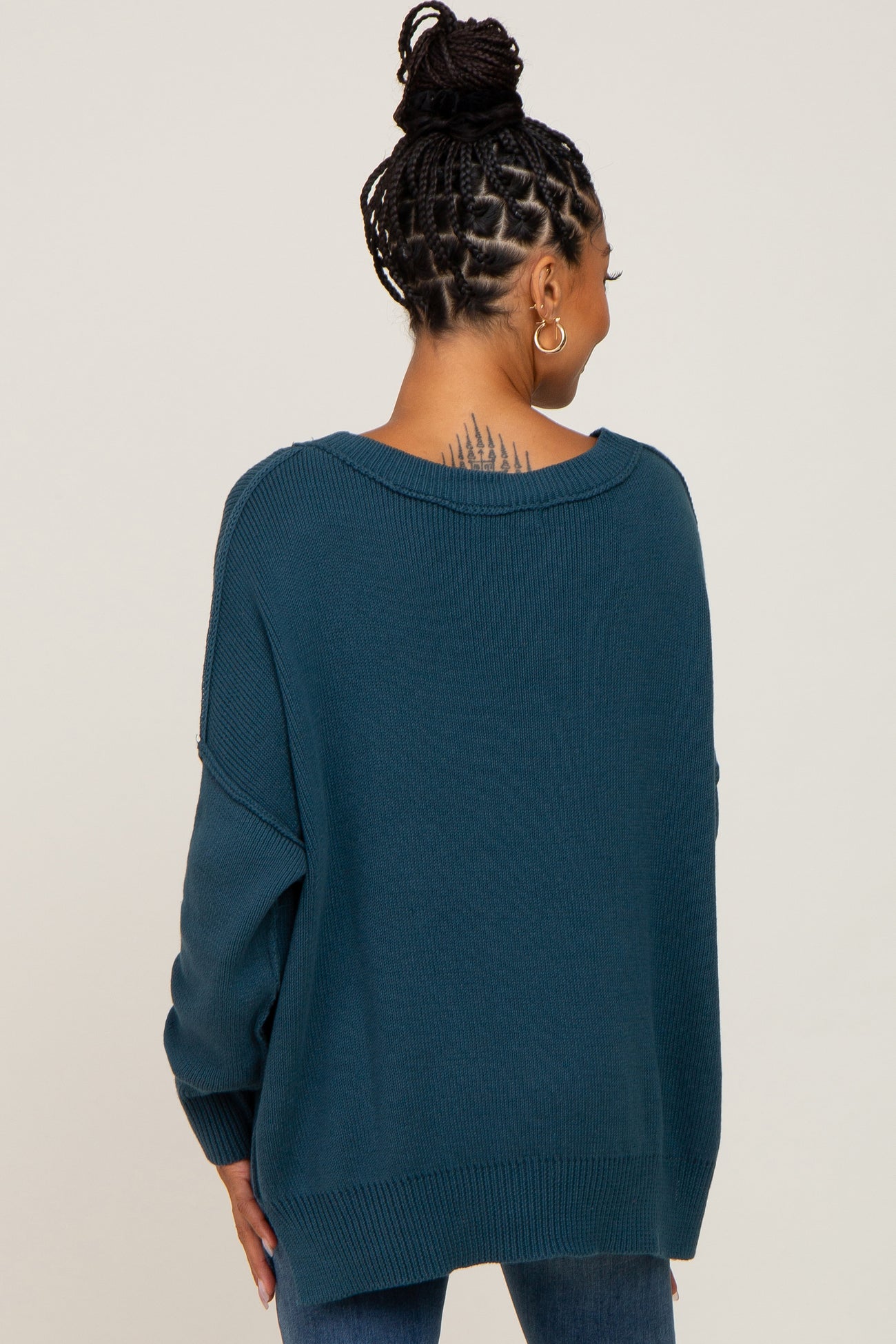woman wearing a teal oversized sweater with a slouchy fit and open back detail