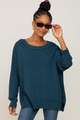 woman wearing a teal oversized knit sweater and stylish sunglasses, smiling at the camera