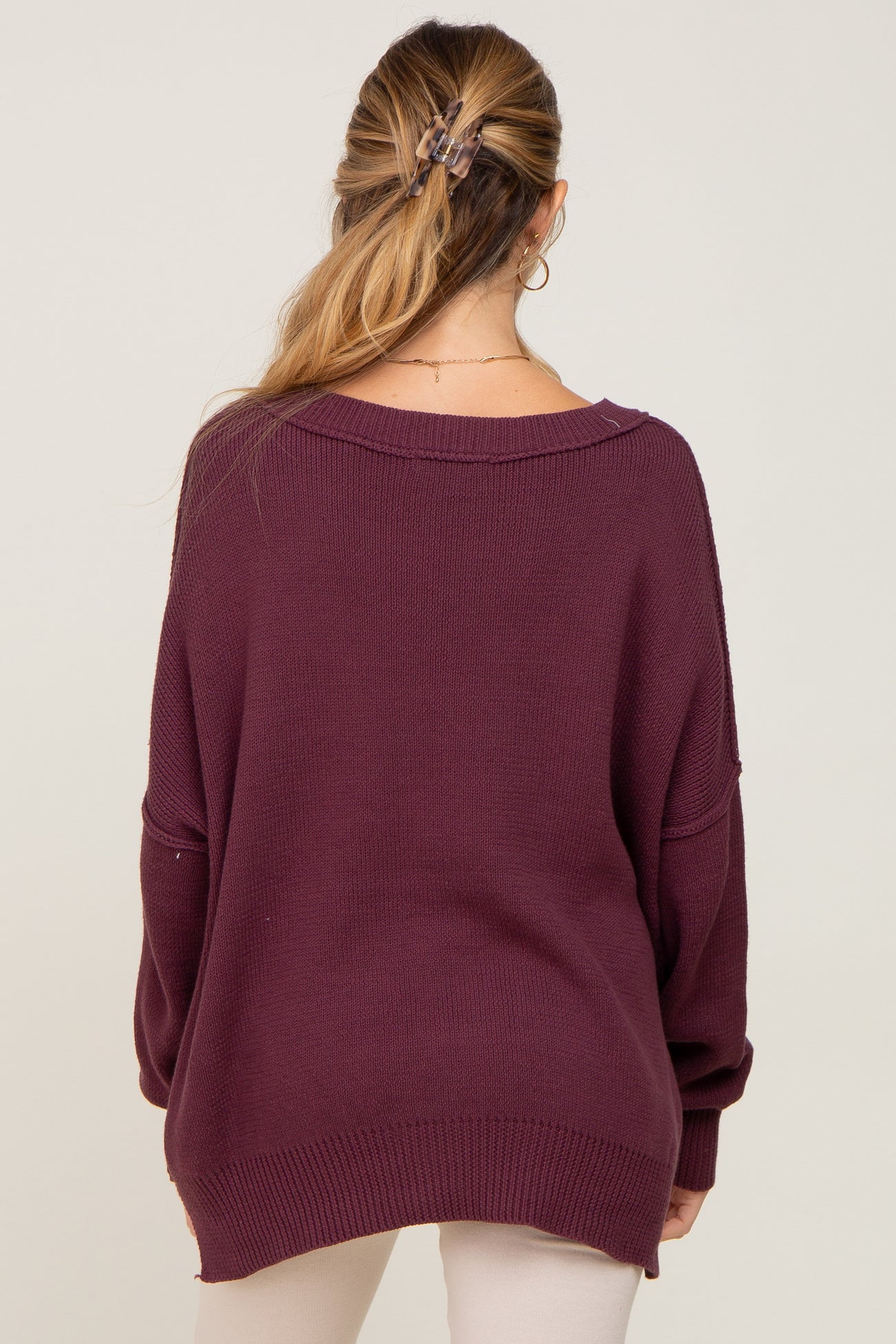 woman wearing a deep burgundy oversized maternity sweater, back view with relaxed fit and drop shoulders