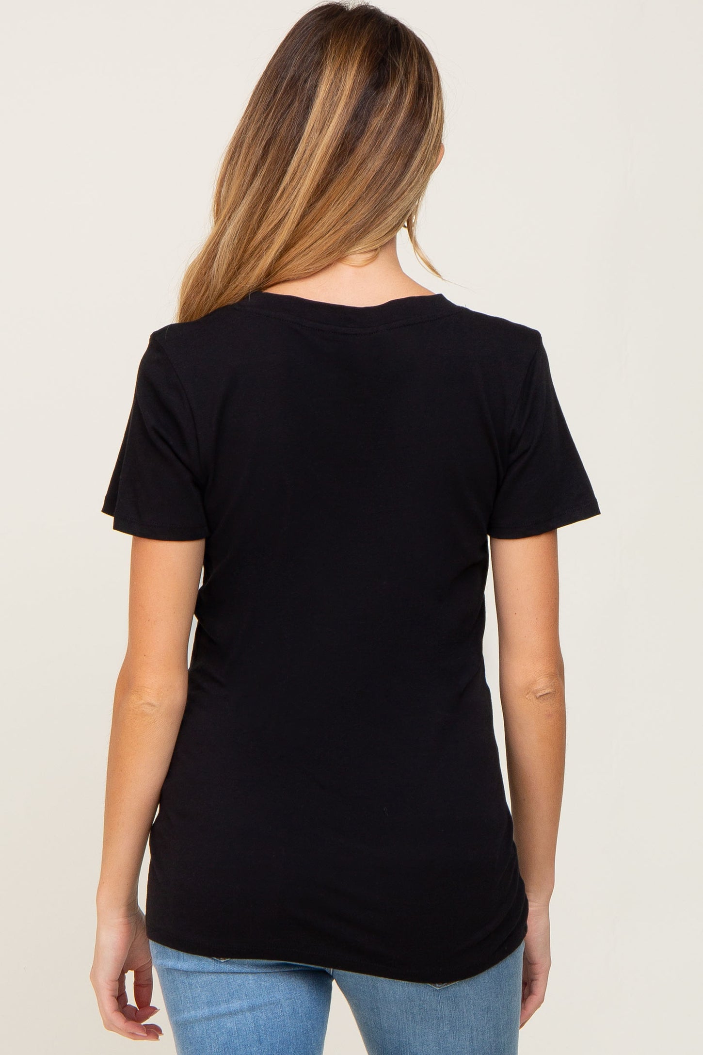 Back view of a woman with long blonde hair wearing a plain black short sleeve t-shirt and blue jeans