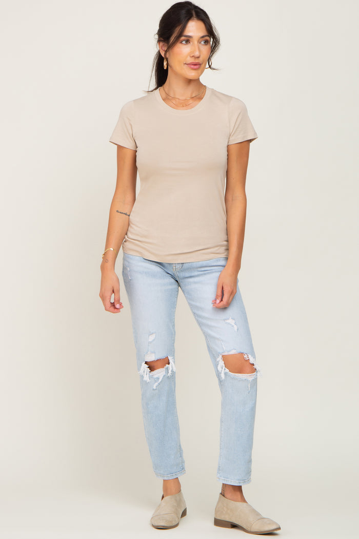 woman wearing a beige short sleeve t-shirt and light blue ripped jeans with beige slip-on shoes