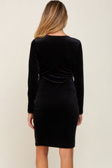 woman wearing a black long sleeve velvet maternity dress, showing the back view