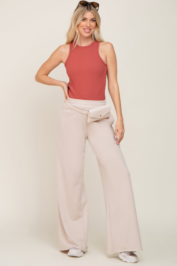 woman wearing a rust ribbed tank top with high-waisted beige wide-leg pants and a matching fanny pack