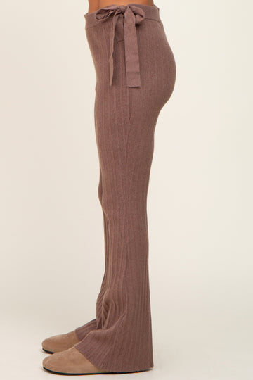 Side view of person wearing mauve ribbed knit flare pants with a tie waist and tan suede slippers
