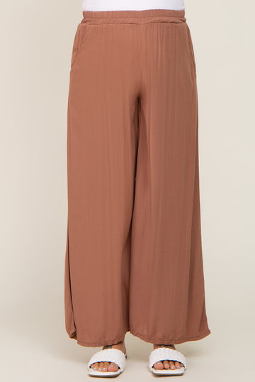 woman wearing brown wide leg pants with elastic waistband and white woven slide sandals