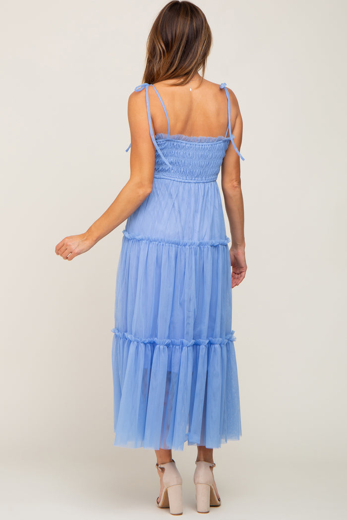 woman wearing a light blue tiered tulle maxi dress with adjustable straps and a smocked bodice