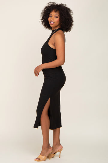 woman with curly hair wearing a black sleeveless ribbed midi dress with a side slit and tan heels