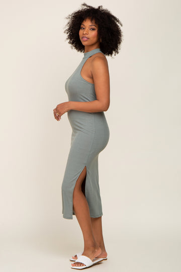 woman wearing a green ribbed midi dress with a high neckline and side slits, standing sideways