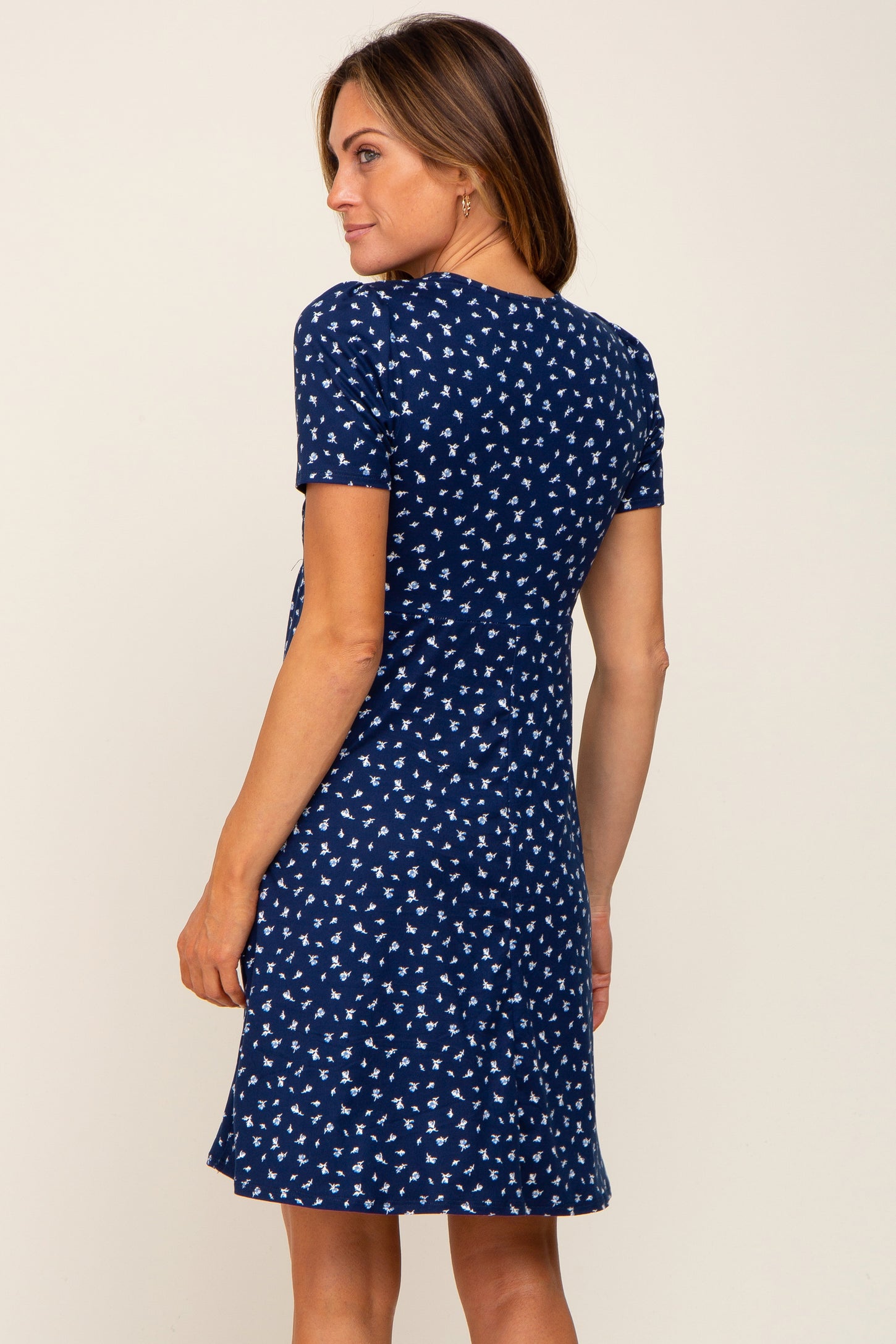 woman wearing a navy blue short sleeve dress with a white floral print and a relaxed fit, seen from the back