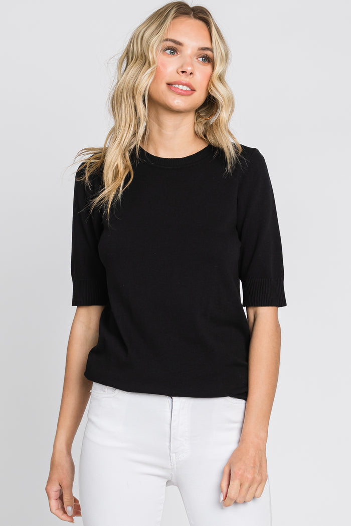 woman wearing a black short sleeve sweater and white jeans