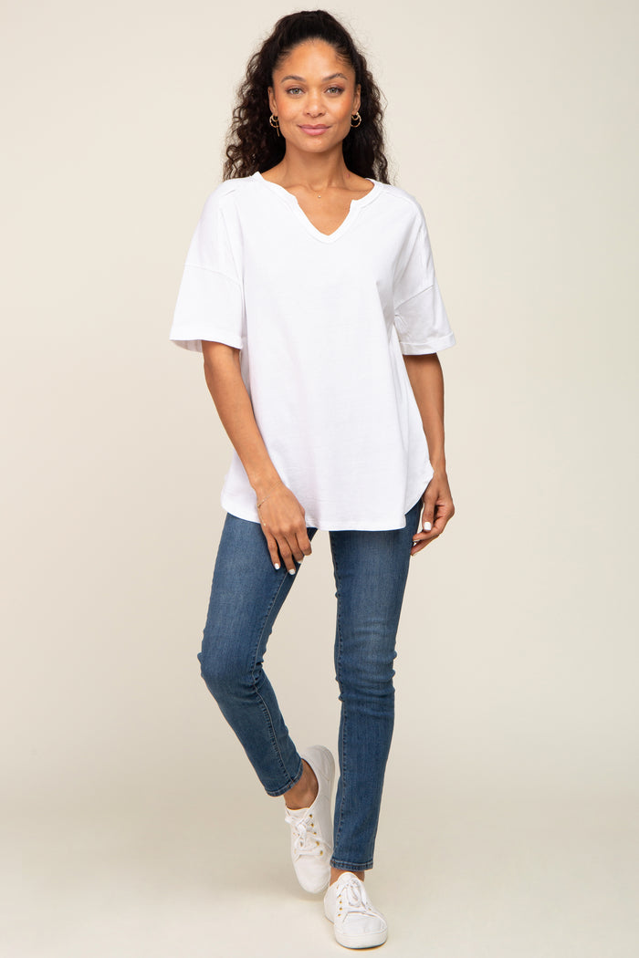 woman wearing a loose white v-neck t-shirt and blue skinny jeans with white sneakers