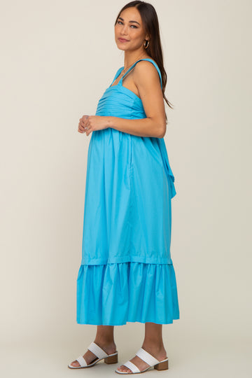 woman wearing a bright blue sleeveless maternity midi dress with ruffle hem and white sandals