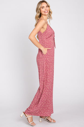 woman wearing a light pink floral maxi dress with a tie front and pockets, posed sideways