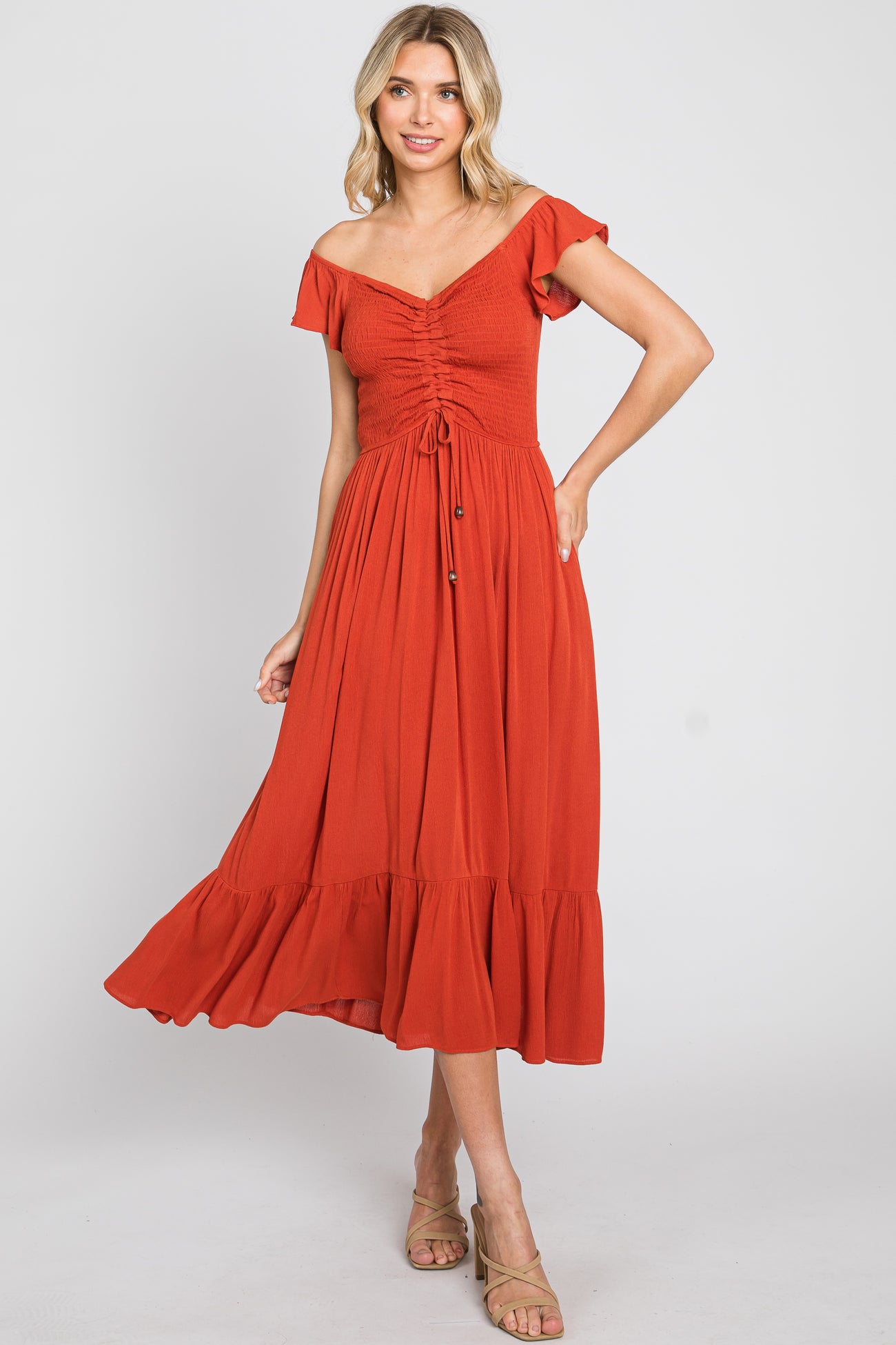 woman wearing a rust red off-the-shoulder midi dress with ruched bodice and ruffled hem