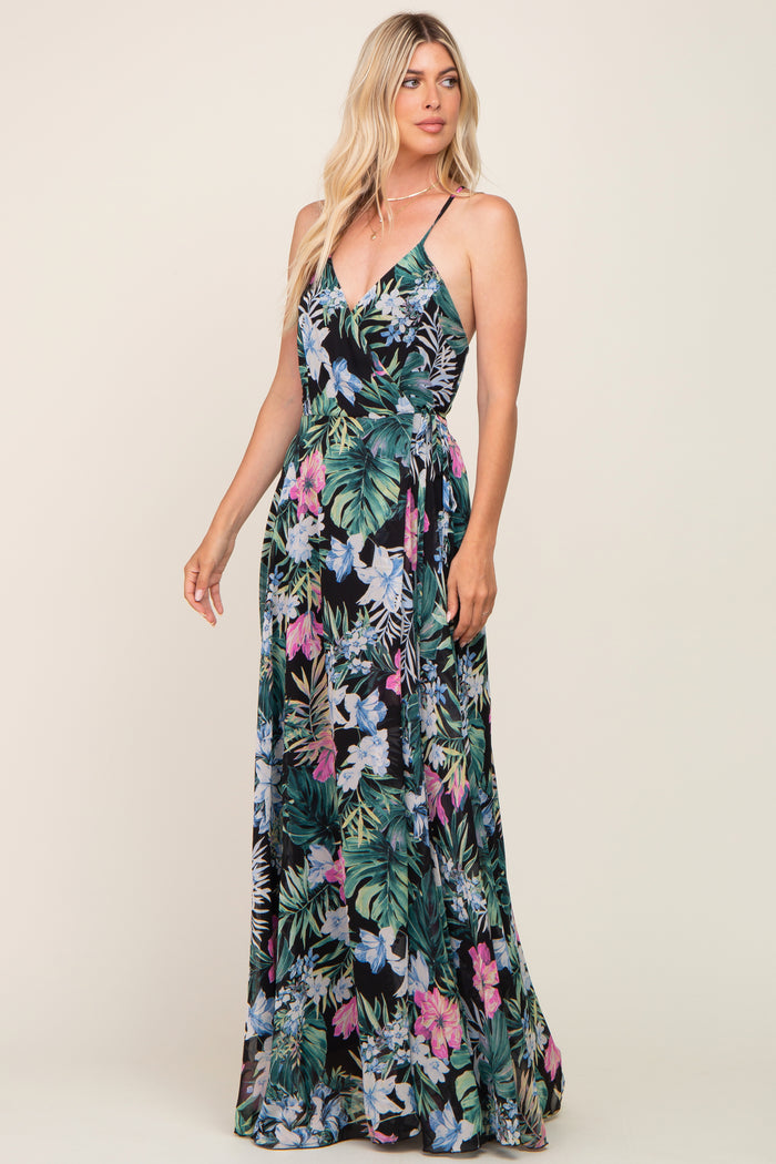woman wearing a tropical floral maxi dress with adjustable spaghetti straps and a tie waist