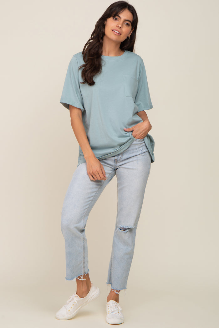 woman wearing a teal oversized t-shirt with a pocket and light wash ripped jeans, standing in casual pose
