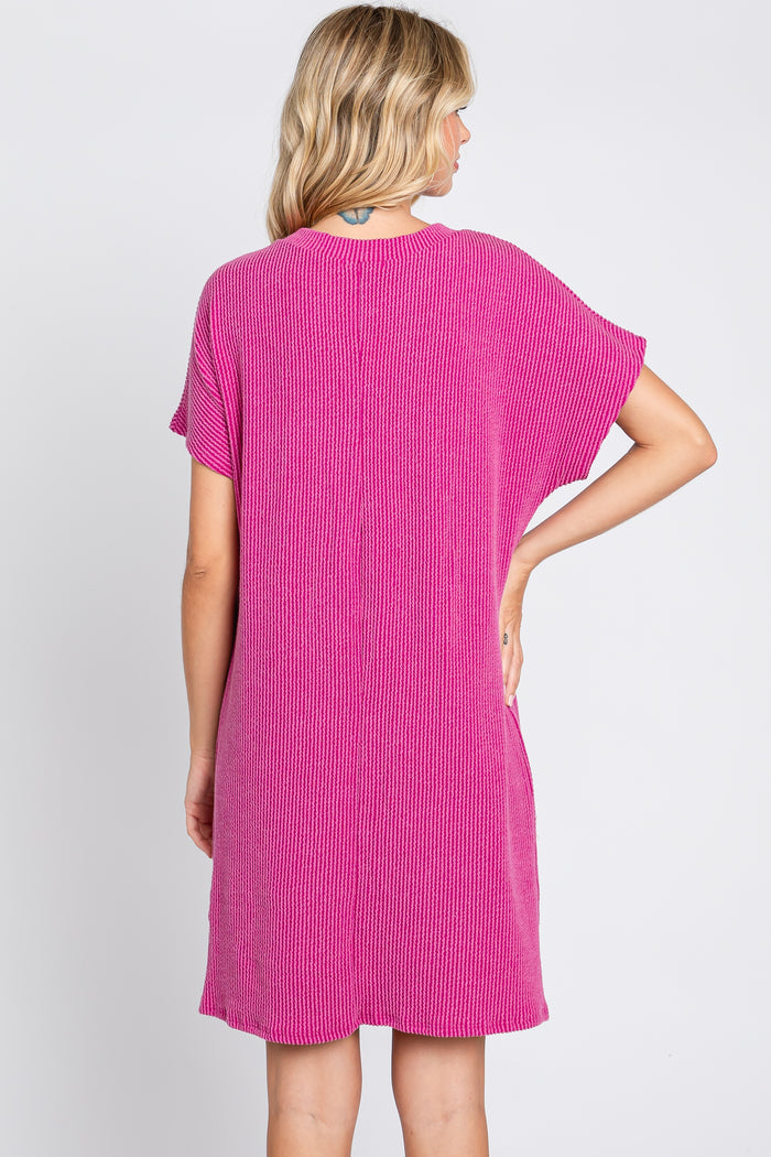woman wearing a bright pink short sleeve knit dress, viewed from the back