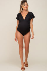 woman wearing a black striped maternity swimsuit with flutter sleeves and a deep v-neck, showing her baby bump