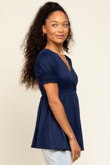 woman wearing a navy blue short sleeve peplum top with smocked details and a v-neckline