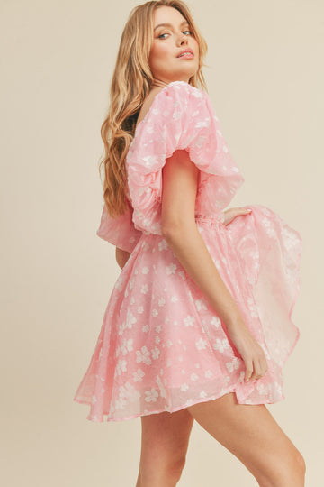woman wearing a pink floral short dress with puff sleeves and a cinched waist