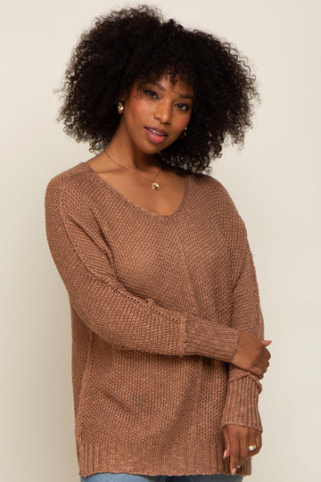woman wearing a brown oversized knit sweater with a v-neckline and long sleeves