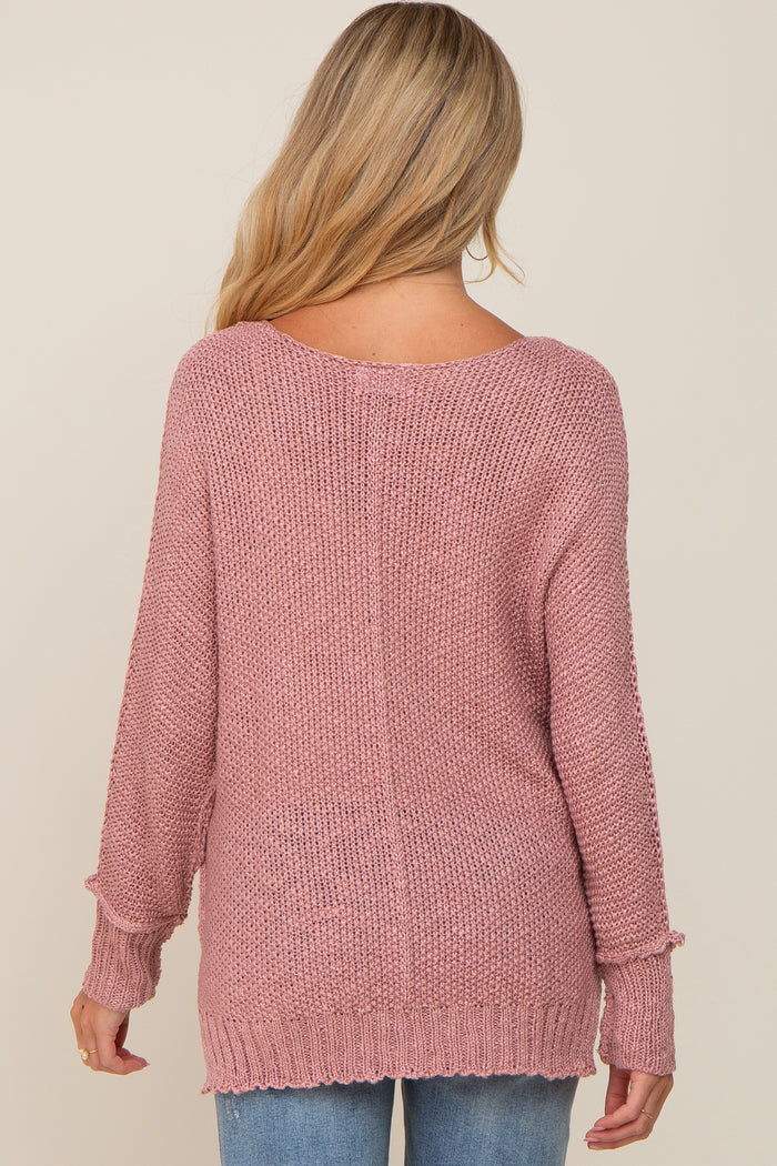 back view of a woman with blonde hair wearing a mauve pink oversized knit sweater and blue jeans
