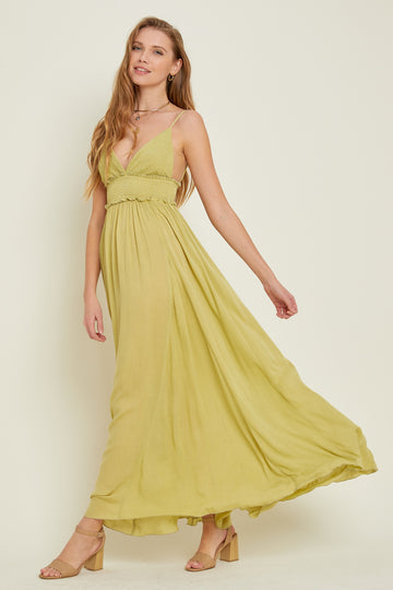 woman wearing a long olive green sleeveless maxi dress with a ruffled bodice and tan block heel sandals