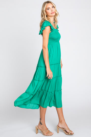woman wearing a green smocked tiered midi dress with ruffle sleeves and tan heeled sandals