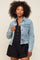 woman wearing a light blue cropped denim jacket over a black playsuit