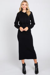 woman wearing a black hooded sweatshirt dress with a fitted silhouette and a drawstring waist, smiling at the camera
