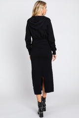 woman wearing a black hooded maxi dress with a back slit and long sleeves, seen from the back