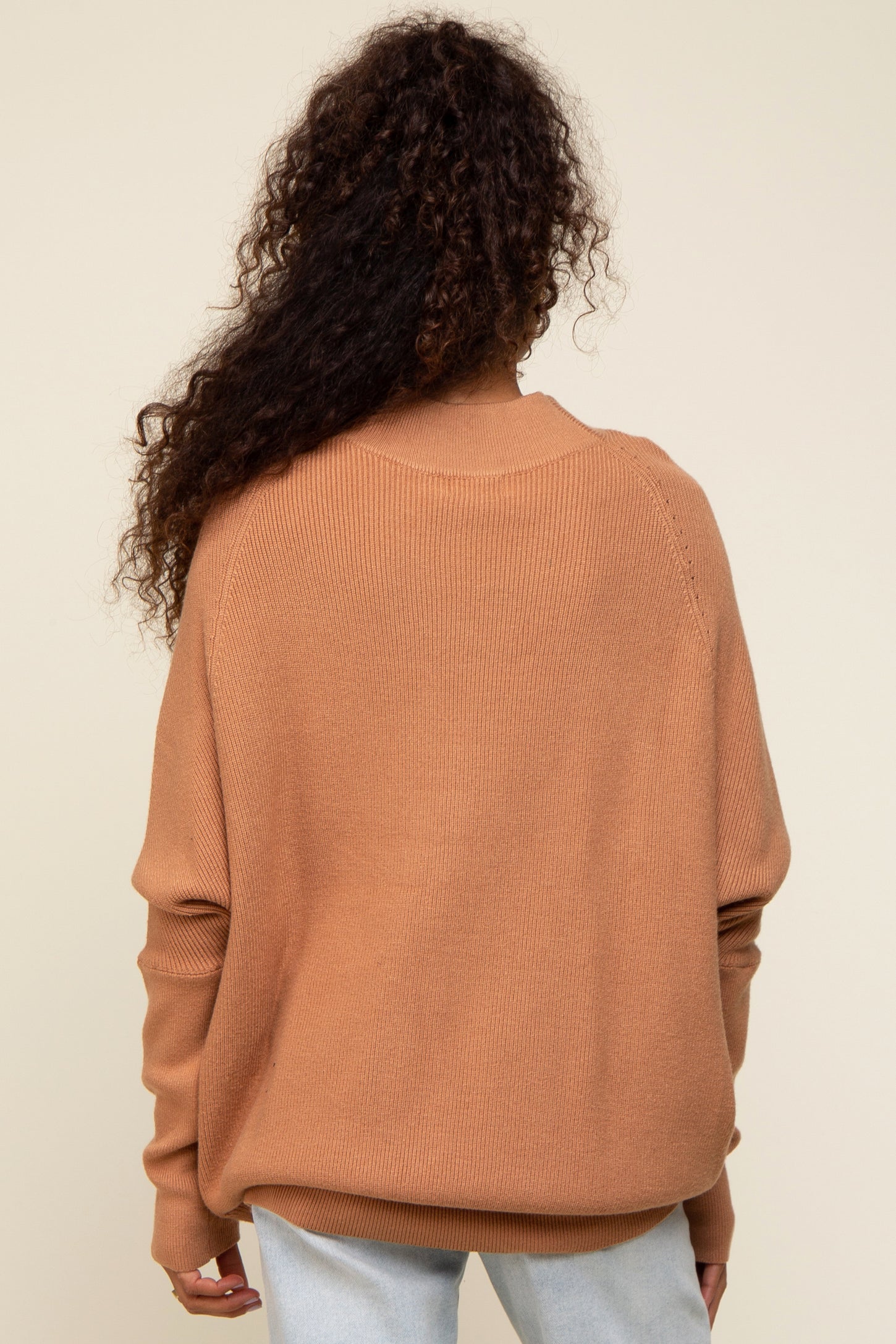 woman wearing a back view of an oversized warm orange knit sweater with long sleeves