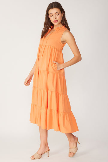woman wearing an orange tiered midi dress with a collared neckline and pockets, standing sideways