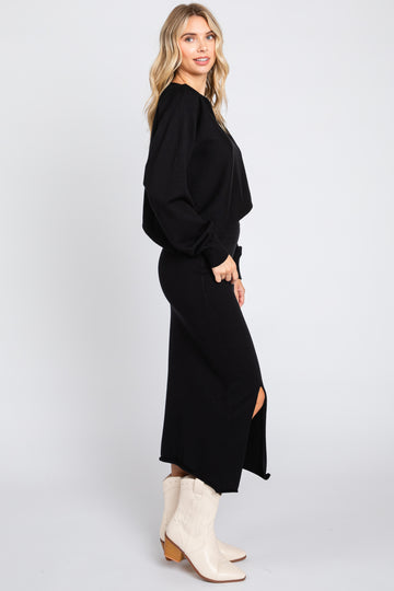 woman wearing a black long sleeve sweater and black midi skirt with side slit and beige cowboy boots
