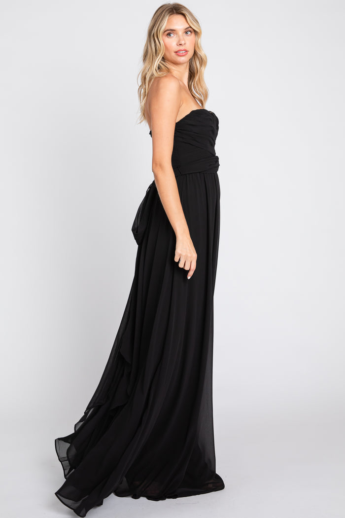 woman wearing a strapless black evening gown with a ruched bodice and a flowing skirt
