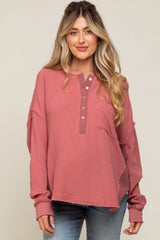 woman wearing a dusty rose maternity top with a henley neckline and oversized fit, paired with denim jeans