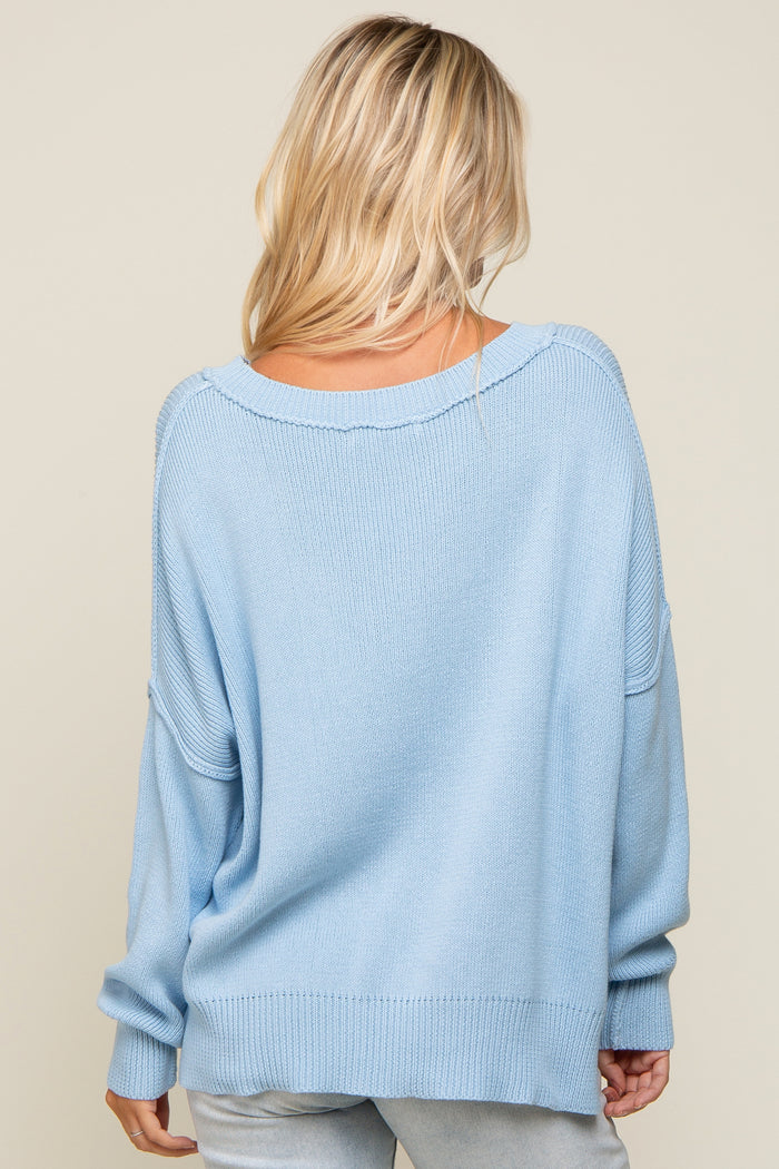 woman wearing a light blue oversized sweater with a wide neckline and dropped shoulders