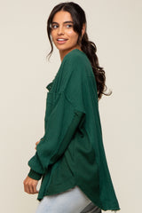 woman wearing a dark green oversized textured knit top with a relaxed fit and raw hemline