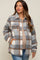 woman wearing a grey and white plaid flannel jacket over a beige maternity top and jeans, showing her baby bump